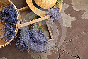 Beautiful lavender flowers and straw hat on cement floor outdoors. Space for text