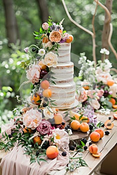 Beautiful layered cake with decoration of fruits, berries and fresh flowers.