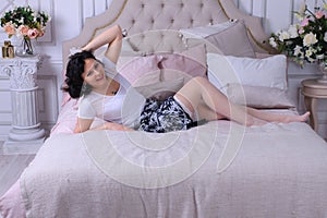 Beautiful legged brunette girl in miniskirt and white stockings posing on sofa