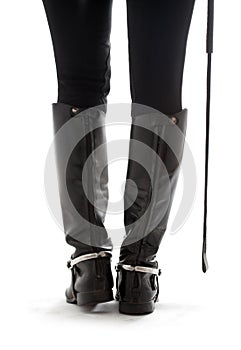 Beautiful legs in black leather horseman boots with riding-crop
