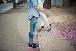 Beautiful legs of young girl in high heels next to the legs Man in pink flower petals, style, fashion, concept, romance