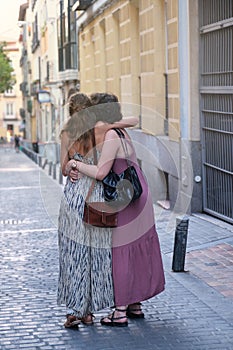 Beautiful lesbian couple wearing hugging in the street, backwards