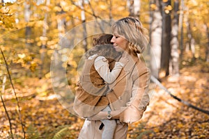 Beautiful lifestyle autumn photo mother and child walks evening in the park, warm sunlight.