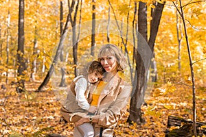 Beautiful lifestyle autumn photo mother and child walks evening in the park, warm sunlight.