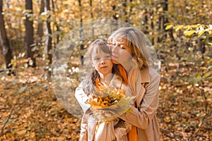 Beautiful lifestyle autumn photo mother and child walks evening in the park, warm sunlight.