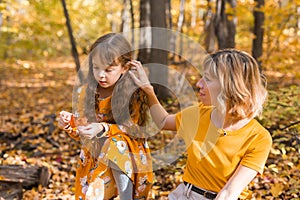 Beautiful lifestyle autumn photo mother and child walks evening in the park, warm sunlight.