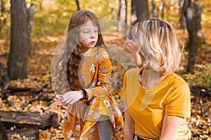 Beautiful lifestyle autumn photo mother and child walks evening in the park, warm sunlight.