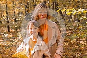 Beautiful lifestyle autumn photo mother and child walks evening in the park, warm sunlight.