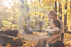 Beautiful lifestyle autumn photo mother and child walks evening in the park, warm sunlight. Copy space.
