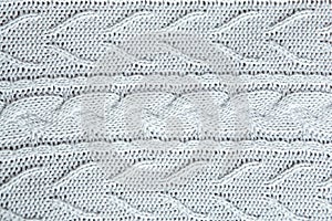 Beautiful light gray knitted pattern, knitted scarf close up. Knitted background