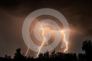 beautiful lightning during a thunderstorm at night in a forest that caused a fire, against a dark sky with rain