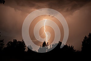 beautiful lightning during a thunderstorm at night in a forest that caused a fire, against a dark sky with rain