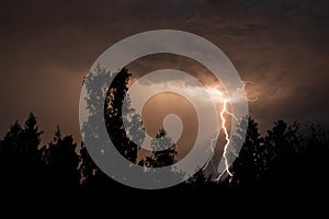 beautiful lightning during a thunderstorm at night in a forest that caused a fire, against a dark sky with rain