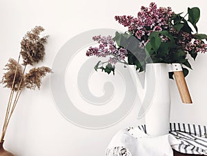 Beautiful lilac flowers in white stylish watering can on white background indoors. Modern decor design, purple lilac in metal