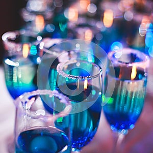 Beautiful line of different colored alcohol cocktails with smoke on a Christmas party, tequila, martini, vodka, and others on part