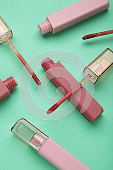 Beautiful lip glosses on a mint background. Vertical photo