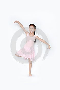 Beautiful little Asian child girl in pink tutu skirt dancing over white background. Children is studying ballet