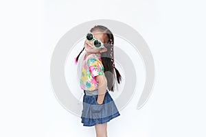 Beautiful little Asian kid girl wearing a flowers summer dress and sunglasses isolated on white background looking camera. Summer