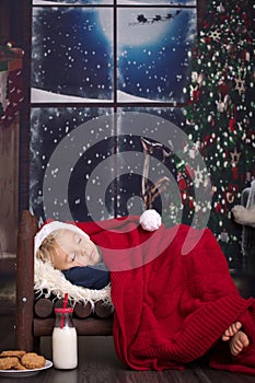 Beautiful little baby boy, sleeping in small wooden bed, waiting for Santa Claus to come and bring presents