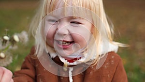 beautiful little baby girl blowing on a dandelion with mother