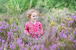 Beautiful little baby girl in purple autumn flowers