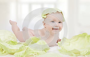 Beautiful little baby with green cabbage