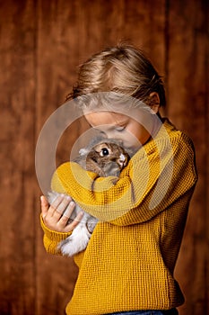 Beautiful little blond child, cute boy, holding small pet rabbit