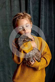 Beautiful little blond child, cute boy, holding small pet rabbit