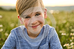 Beautiful little boy in daisy field on sunset, summertime