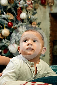 Beautiful little boy dreaming of cottages under the Christmas tree. Christmas concept and children waiting for a miracle