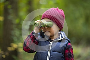 Beautiful little boy looking through binoculars wrong way