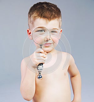 Beautiful little boy looking through a magnifying glass