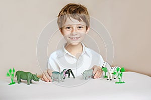 Beautiful little boy, smiling at camera, animals around him, indoor shot