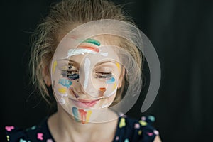 Beautiful little caucasian girl with face painted with colorful paint smiling happy