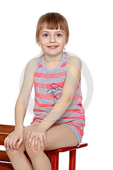 The girl is sitting on a large toy wooden car.