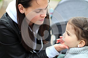 beautiful little cheerful smiling girl with her mother on a walk in the street