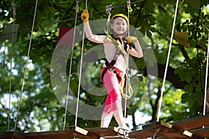 Beautiful little child climbing and having fun in adventure Park. Cargo net climbing and hanging log. Carefree childhood