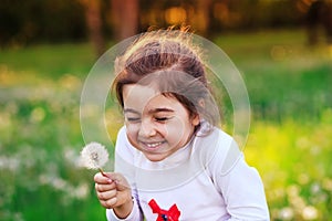 Beautiful little child with dandelion flower in sunny summer par