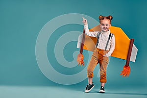 Beautiful little child girl with homemade cardboard plane wings, imagination and girl power concept