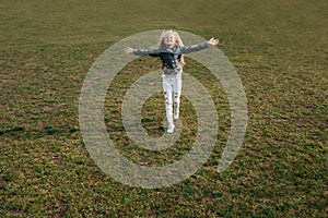 Beautiful little child girl runs on a green lawn