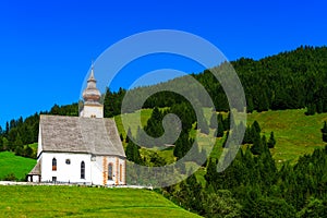 Beautiful little church in Alps. Sunny day, green grass on the h