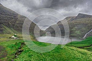 Beautiful little church, with a grassy roof, against the backdrop of beautiful mountains, and dramatic clouds. Faroe