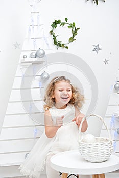 Beautiful little curly-haired girl in a white dress, shot in bright studio decorations