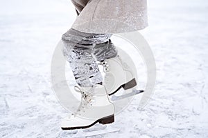 Beautiful little cute girl learn to skate on ice skating rink in park. Fall down and have fun. Stylish look, warm woolen coat,