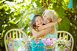 Beautiful little daughter hugs mom in the garden in summer