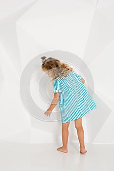 Beautiful little fashion model on white studio background. Portrait of cute girl posing in studio