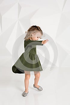 Beautiful little fashion model on white studio background. Portrait of cute girl posing in studio