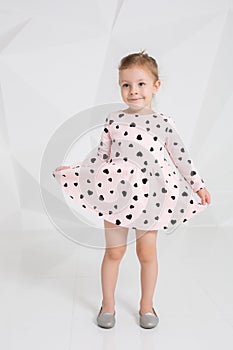 Beautiful little fashion model on white studio background. Portrait of cute girl posing in studio