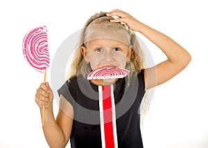 Beautiful little female child with sweet blue eyes and long blond hair eating huge lollipop spiral candy