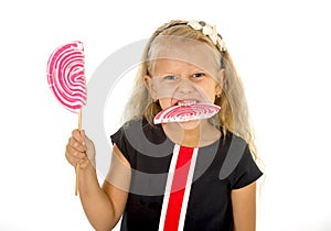 Beautiful little female child with sweet blue eyes and long blond hair eating huge lollipop spiral candy